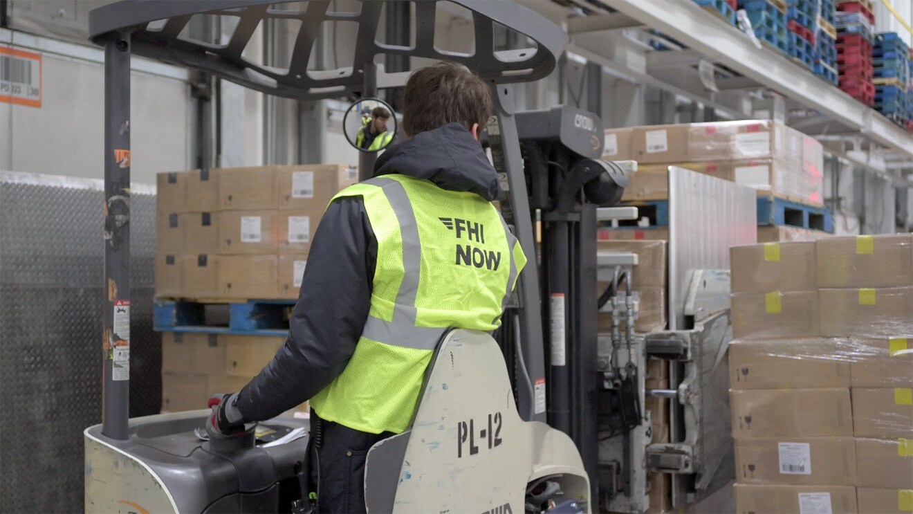 An image of an FHI worker on a pallet jack in a warehouse.